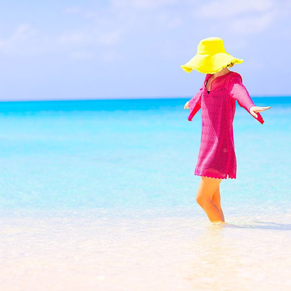 woman at the beach with yellow hat and pink dress 