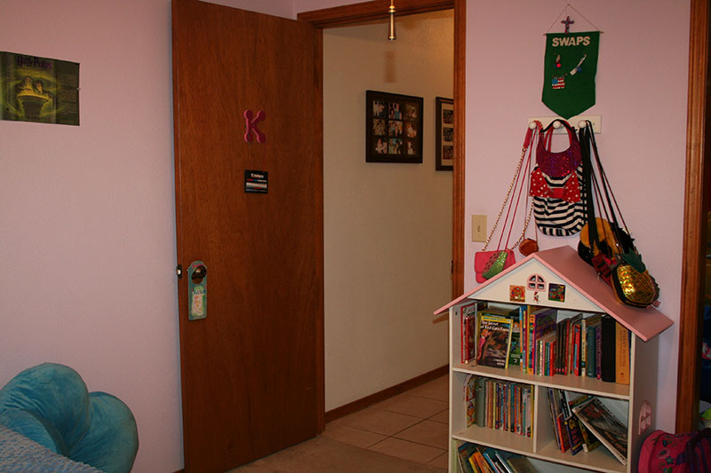 bedroom door with pink walls, door, and doll house