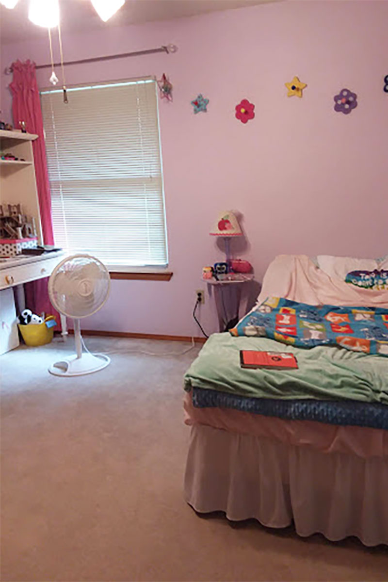 a One Room Challenge before image with flowers on the wall, bed, and electric fan