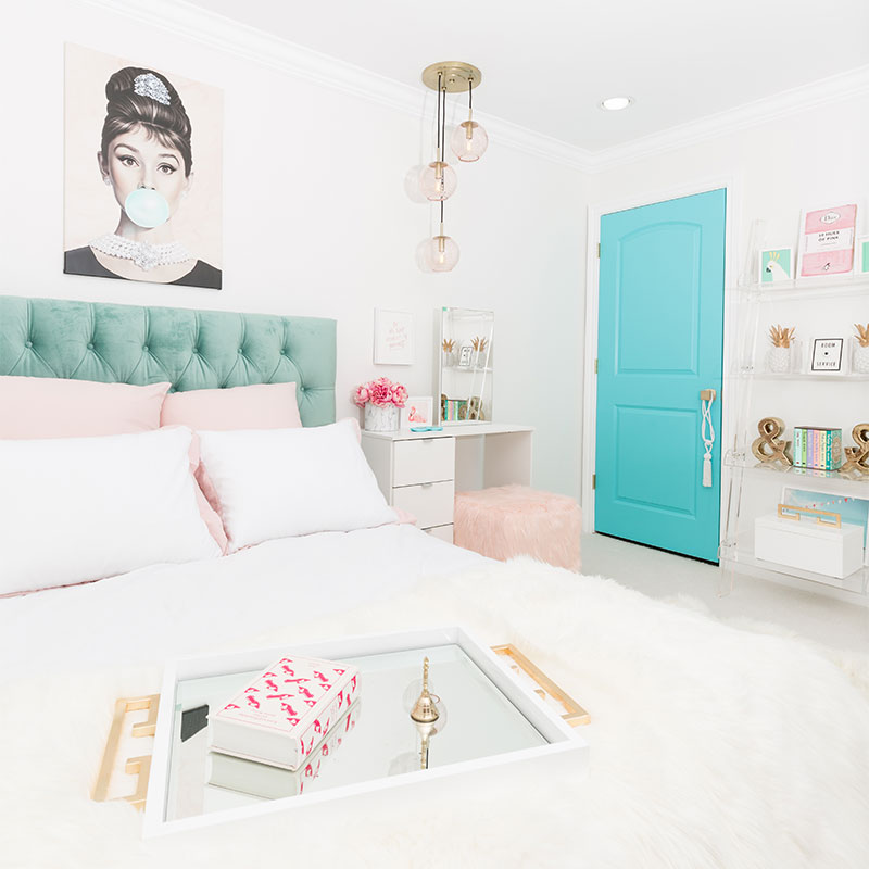 bedroom with white walls, painting, bed with head board, and aqua blue door
