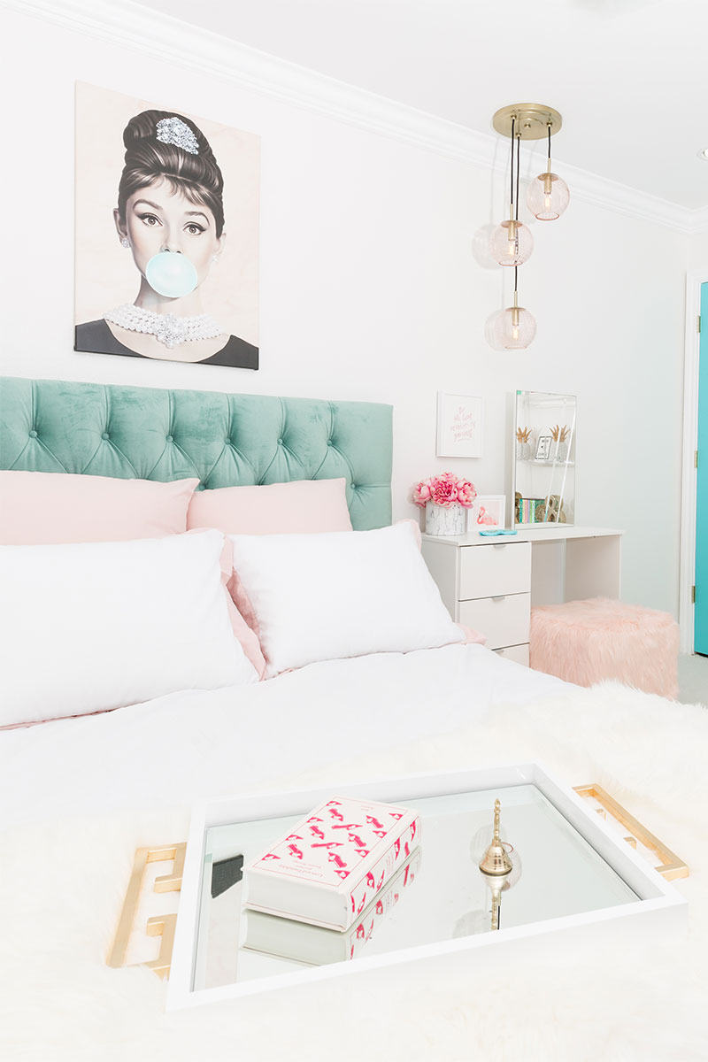 bedroom with bed and aqua head board, chandelier, vanity table, and aqua blue door