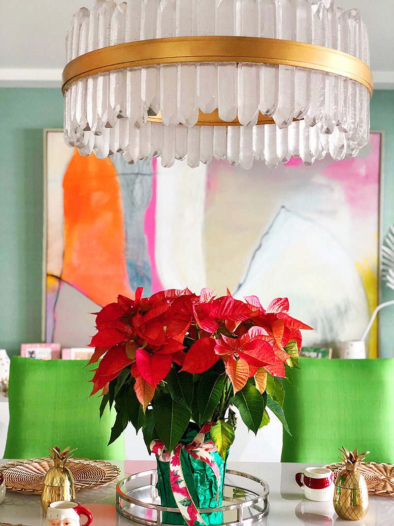 a chandelier and a poinsettia plant, gold pineapple, and mugs as Christmas Decor in Palm Springs