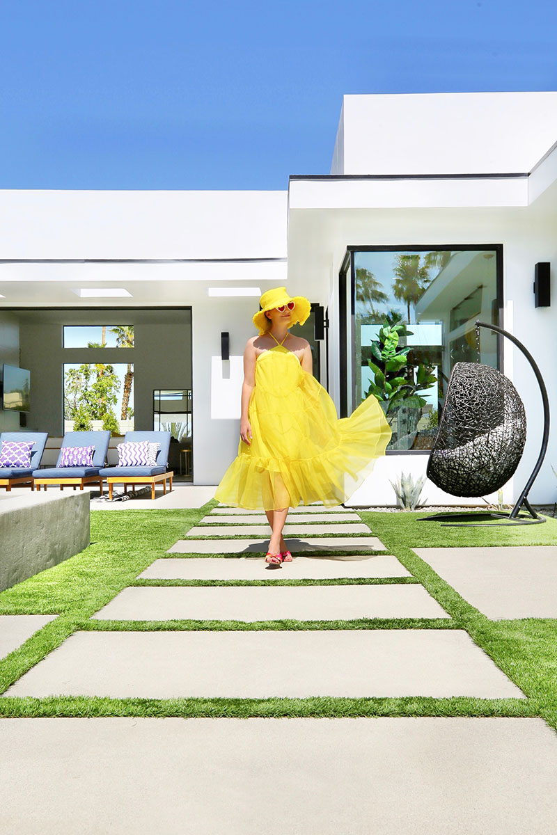 Woman wearing a bright yellow dress walking at the poolside