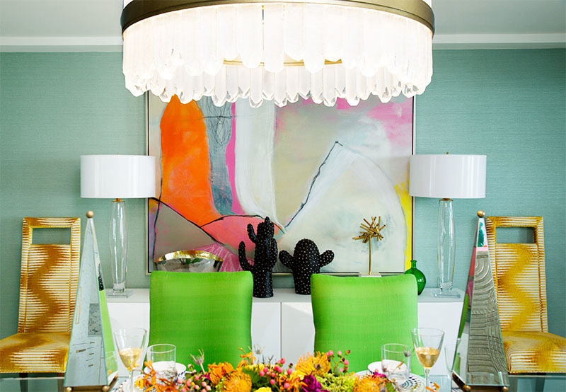 two dining room chairs in green, two extra chairs, a painting, and chandelier