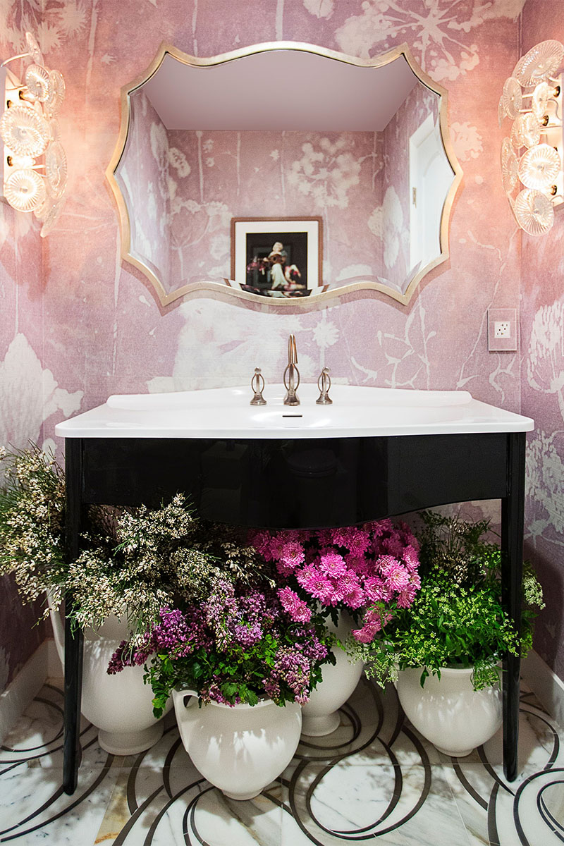 powder room with pink walls and flowers below the sink