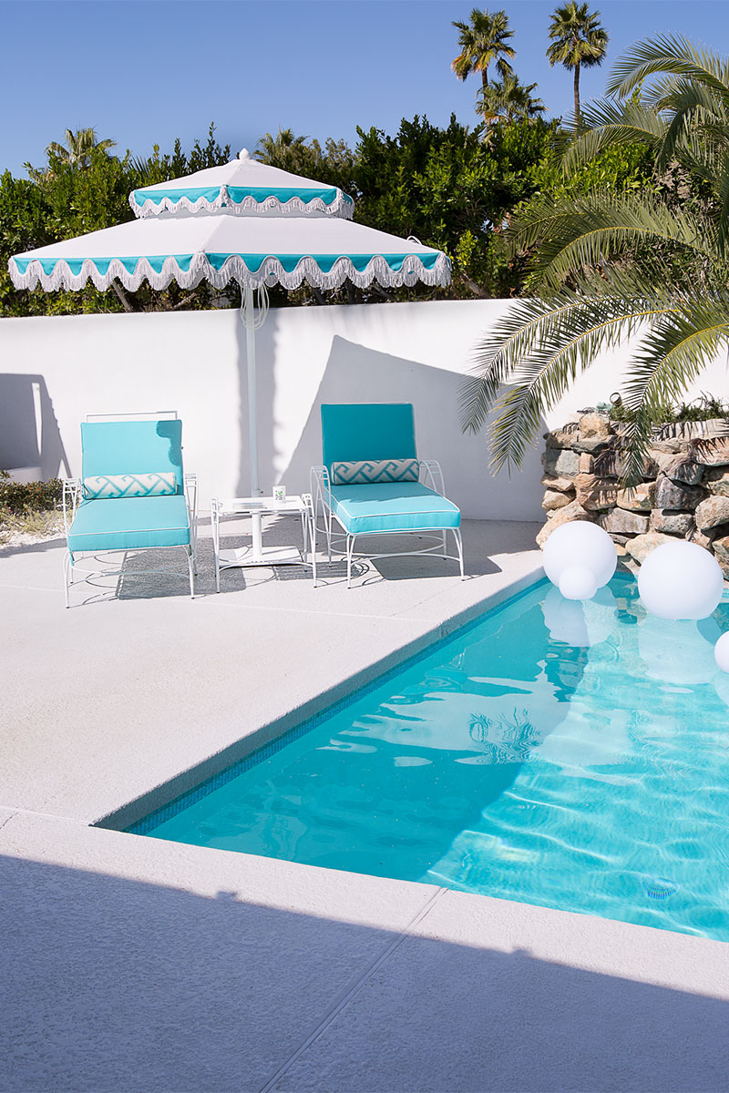 poolside with two lounge chairs in blue and a pool umbrella 