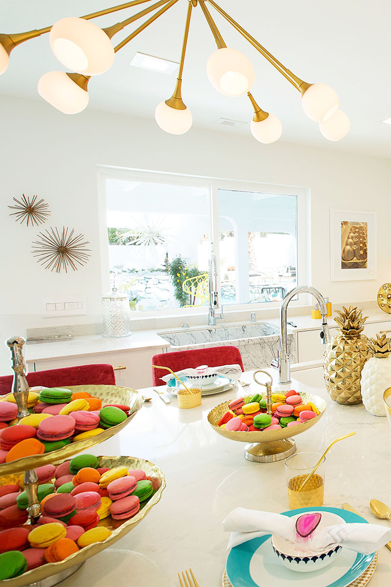 macaroons on the kitchen island, gold pineapple decorations, and a chandelier