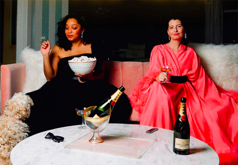two women drinking wine and eating popcorn for classic movie club