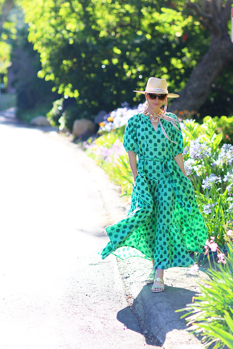 Fashion blogger Kelly Golightly wearing a green breezy summer dress and straw hat 