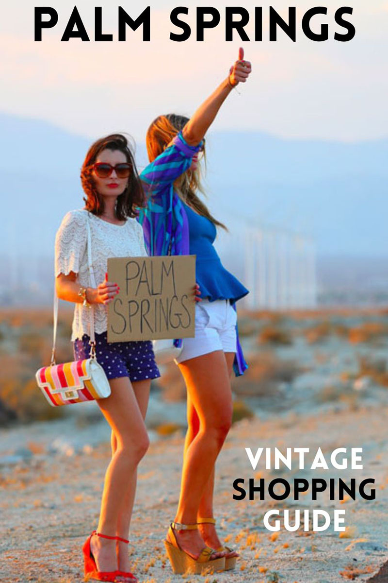 Kelly Golightly shares her Palm Springs Vintage Shopping Guide while holding up a cardboard sign that reads Palm Springs with windmills in the background.