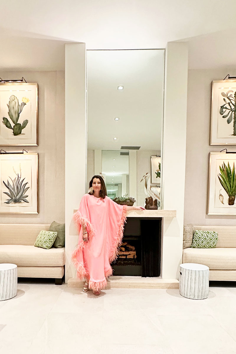Top fashion blogger Kelly Golightly wears a floor-length feather caftan in a pastel pink hue.